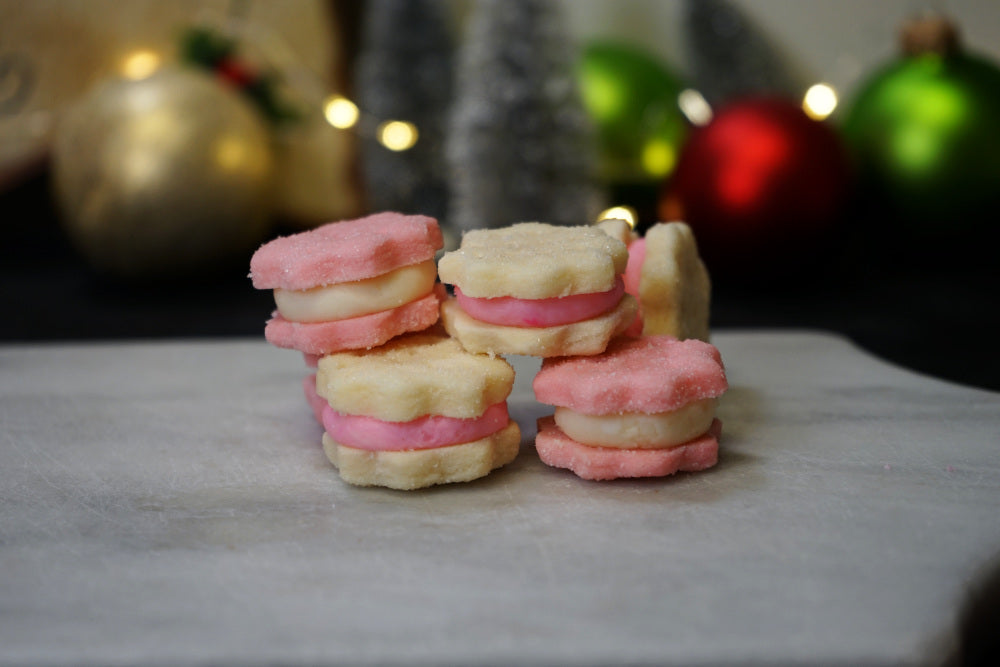 A cream wafer Christmas cookie with either a white filling sandwiched between two pink wafers or pink filling sandwiched between two white wafers.