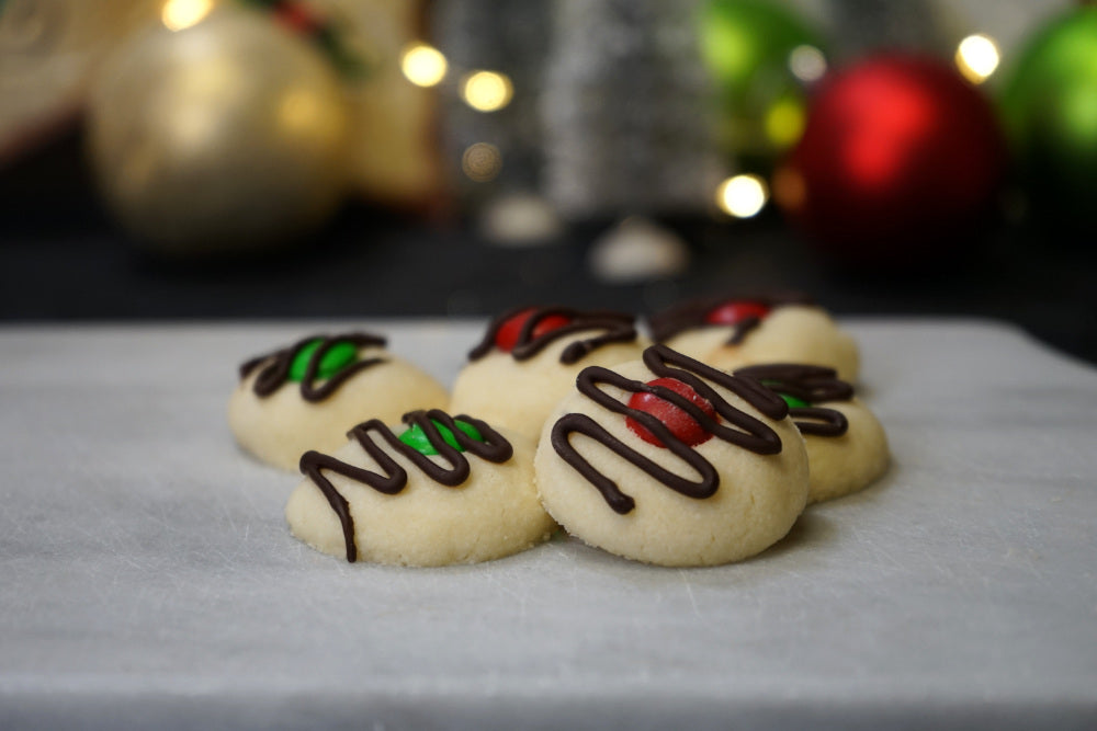 Drizzled shortbread Christmas cookies with an M&M in the center.